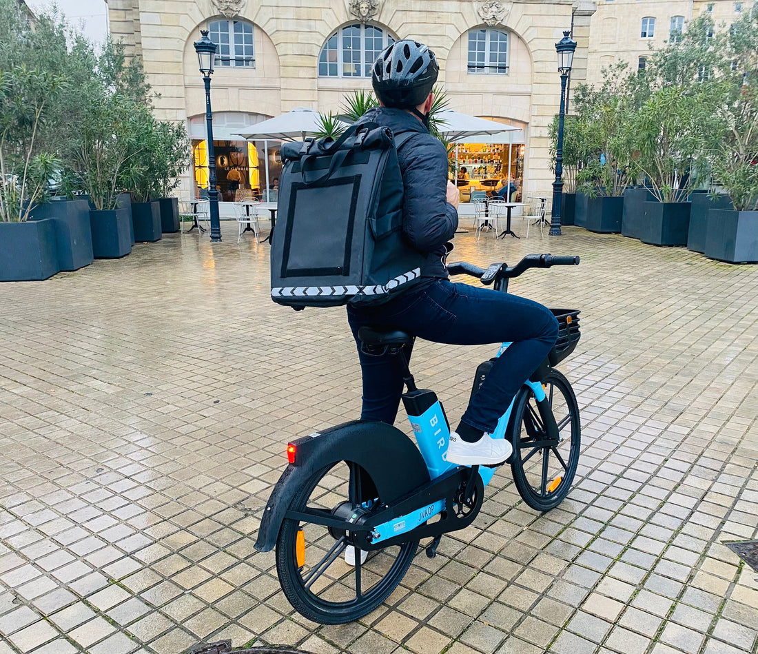 Maaltijdbezorger op de fiets met zwarte isothermische bezorgtas van PAKERS voor Bolt Food in Nederland