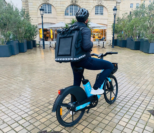 Bezorger op een e-bike met isothermische PAKERS-bezorgtas op weg naar een klant in Nederland