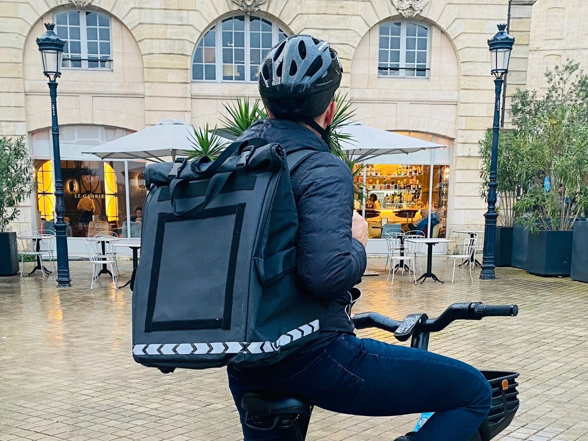 Livreur à vélo sous la pluie avec le sac de livraison PAKERS 74L isotherme et étanche