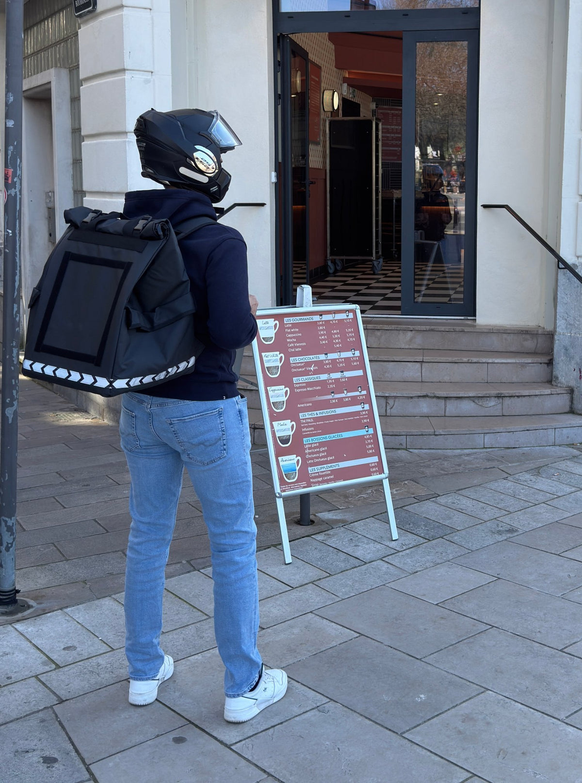 Livreur avec le sac de livraison PAKERS 74L devant un restaurant, prêt à récupérer une commande